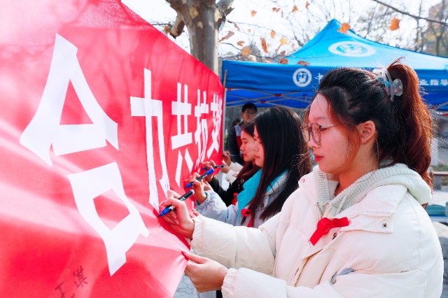 20231127中國石油大學（華東）青年學子在合力共抗艾滋的條幅上簽字，表達抗擊艾滋病的決心和信心  .jpg