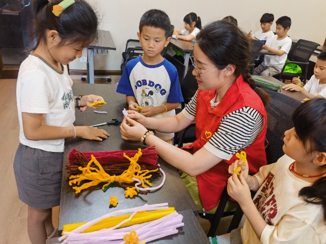 7月12日，在泰州市海陵區(qū)城東街道林湖社區(qū)，泰州市大浦小學(xué)“綠葉”暑期公益班的老師正在教孩子們一起做手工2（拍攝者：泰州市大浦中心小學(xué)  陳惠婷）.jpg